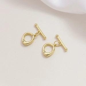 Nahaufnahme der goldenen OT-Knebelverschlüsse für DIY-Schmuck auf weißem Stoffhintergrund