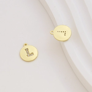 Detailed view of round gold-plated letter L charms with inlaid cubic zirconia and back vents