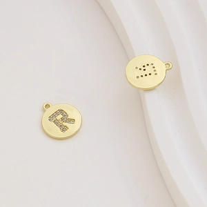 Macro view of gold-plated letter R charm with cubic zirconia inlay for DIY jewelry