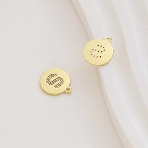 Macro detail of gold-plated letter S pendant with zircon inlay and hollow back design