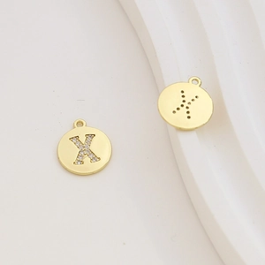 Macro detail of gold-plated letter X pendant with sparkling cubic zirconia inlay