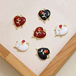 Primer plano de colgantes de corazón con detalle de rosa en esmalte rojo, negro y blanco