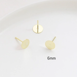 Macro detail of 6mm gold-plated flat round earring studs with polished surface finish