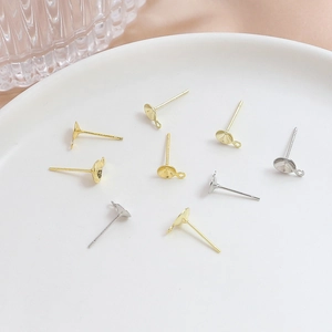Gold- und silberne DIY-Ohrstecker mit Stiftplatte und Öse in einer weißen Keramikschale