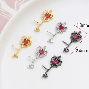Detailed view of key-shaped jewelry pendants in gold and silver with red heart zircon