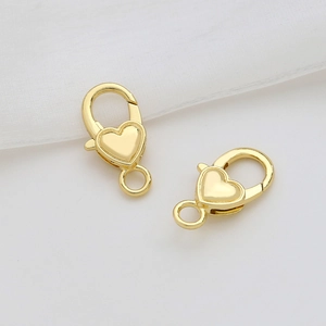 Détail macro de deux fermoirs mousquetons en forme de cœur dorés pour bijoux DIY