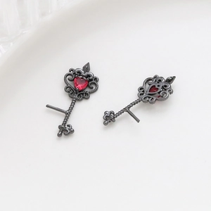 Detail of vintage black key earrings with red heart gemstone and intricate hollow pattern