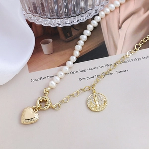 Close-up of a gold heart locket and micro-pave pendant on a pearl-link chain necklace
