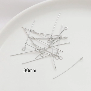 Macro shot of 30mm silver eye pins for DIY jewelry making on white ceramic tray