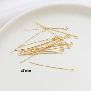 Detailed view of 40mm 14k gold plated eye pins for DIY jewelry making on white tray