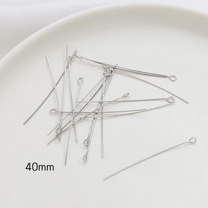 Detail of 40mm silver-plated jewelry eye pins on a white tray for DIY handmade crafting