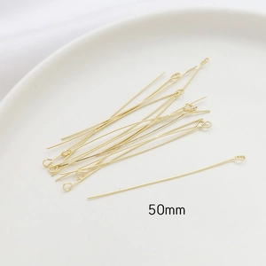 Close-up of 50mm gold-plated eye pins for DIY jewelry making on white ceramic tray