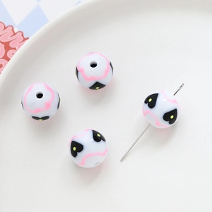 Close-up of acrylic round beads with pink waves and black heart patterns for DIY jewelry