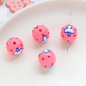 Macro detail of pink acrylic floral beads with colorful printed patterns for DIY jewelry