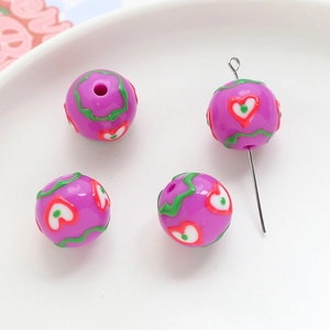 Macro view of purple acrylic beads with green wave lines and red heart patterns for DIY jewelry