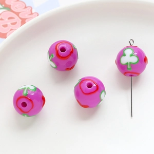 Macro shot of purple acrylic floral beads with white clover and red flower patterns