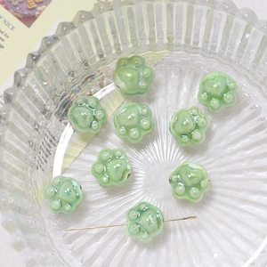 Detailed view of light green ceramic cat paw beads on a metal pin for DIY jewelry making