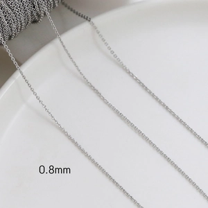 Close-up of 0.8mm silver plated chain link on white ceramic plate for DIY jewelry making