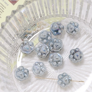 Macro shot of iridescent ceramic cat paw beads with blue pearl glaze for DIY jewelry making