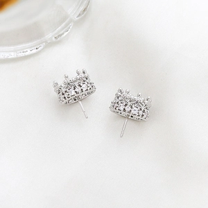 Detail view of silver crown earrings with cubic zirconia inlay on white silk fabric