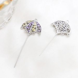 Macro detail of gold-plated umbrella jewelry pins with colorful zircon inlay and filigree