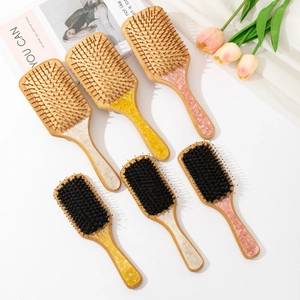 Bamboo hairbrush set with natural wooden bristles and elegant marble resin handles on magazine