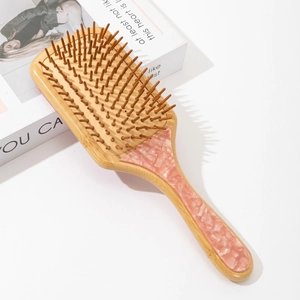 Detailed macro view of bamboo massage hairbrush with pink marble acetate inlay detail