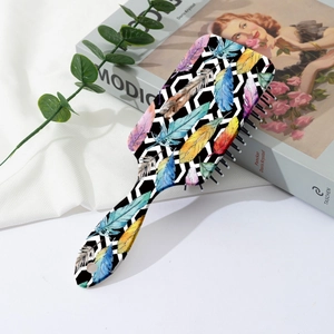 Detail of colorful feather print cushion hairbrush with massage bristles on a stylish book