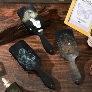Artistic massage hair brushes featuring starry sky lover prints on a dark wooden surface
