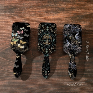 Three air cushion hair brushes with butterfly and tree of life patterns on wood background