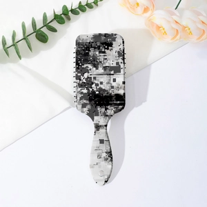 Detail of grey glitch art pattern on the back of a paddle hairbrush with hanging hole