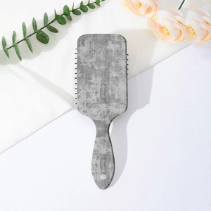 Detail view of the rectangular massage hairbrush with gray marble texture on white background