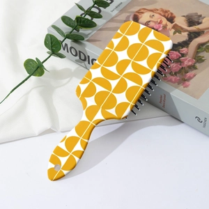 Detail of cushion hairbrush with yellow geometric patterns next to an art book