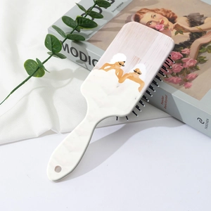 Detail of white hairbrush with fashion illustration on cushioned back for scalp massage