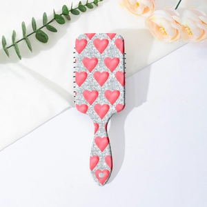 Detail of glitter silver hairbrush with pink hearts on a soft floral background
