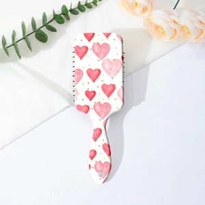 Detail of square air cushion hairbrush with pink heart pattern and massage bristles