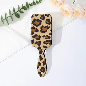 Close-up of leopard print air cushion hairbrush with a hanging hole on white fabric
