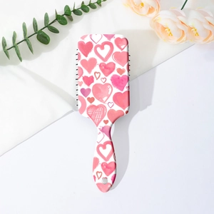Detail view of heart-patterned hairbrush back with hanging hole on a soft background