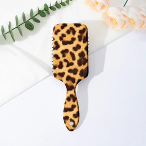 Detail of leopard print paddle brush with ergonomic handle and elegant floral background