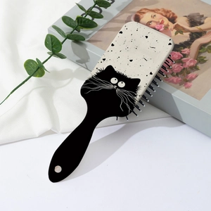 Cute black cat cartoon hair brush with massage air cushion on a soft fabric background