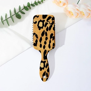Detailed close-up of a large leopard print cushion hairbrush on a floral silk backdrop