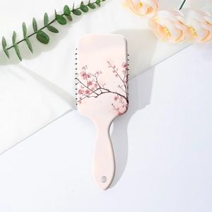 Detail of pink paddle brush with floral cherry blossom print on a soft white fabric background