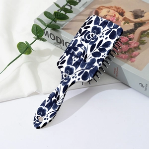 Detailed view of the square paddle brush featuring blue floral patterns on a white background