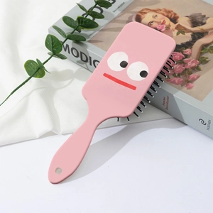 Brosse à cheveux cochon rose avec coussin d'air et picots massants sur livre d'art