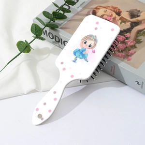 Détail d'une brosse à cheveux blanche avec imprimé fille sur fond de tissu doux