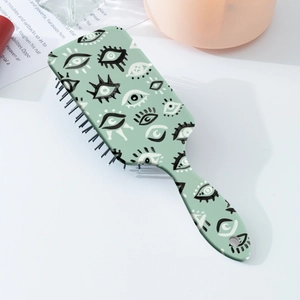 Détail de brosse à cheveux vert clair avec motif œil artistique sur bureau blanc