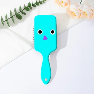 Macro shot of blue air cushion hairbrush with large cartoon eyes and purple nose