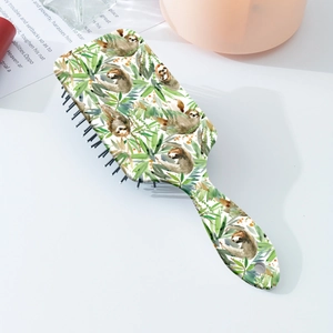Detail of paddle hairbrush showing green sloth print and ergonomic handle with hanging hole