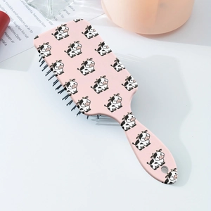 Close-up of the pink cartoon cow pattern on the portable air cushion hairbrush handle