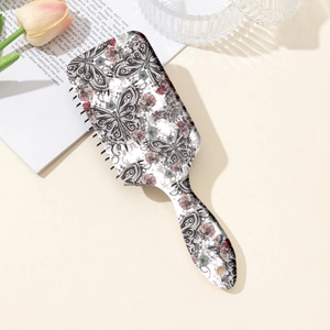 Brosse à cheveux massante avec motif papillon et fleurs sur une mise en scène bureau